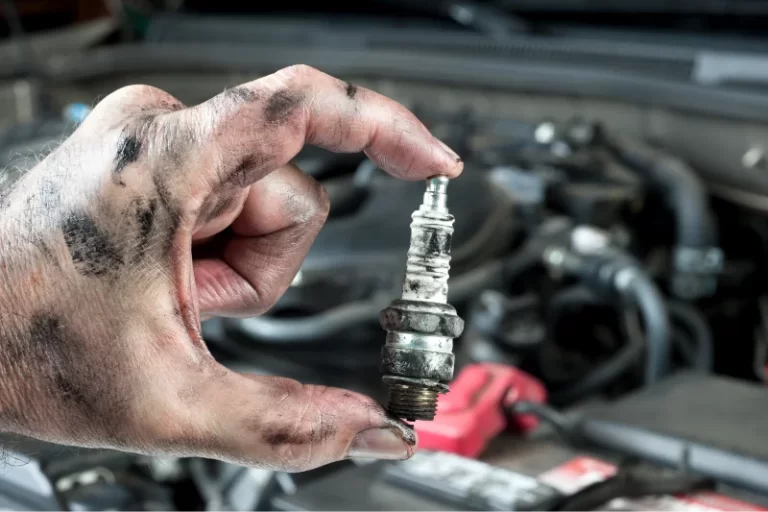 mechanic holding a spark plug before tuning up the kia
